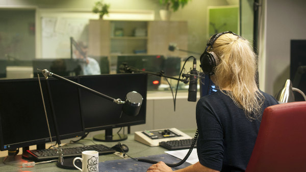 Sie sehen ein Radiostudio mit einer Moderatorin am Mikrofon.