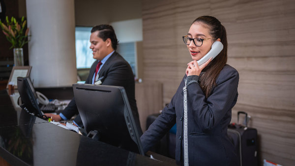 Sie sehen die Rezeption eines Hotels mit zwei Mitarbeitern.