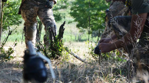 Sie sehen zwei Soldaten beim Entschärfen von Granaten.