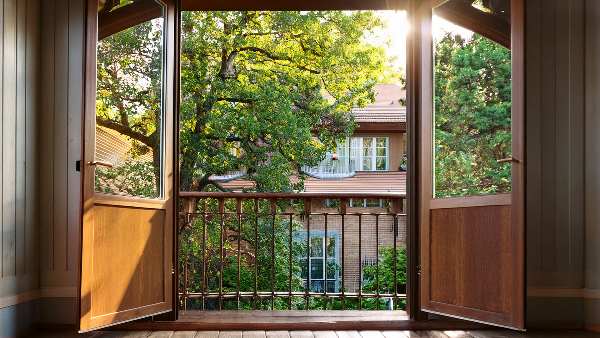 Sie sehen eine offene Balkontür mit einem Geländer davor.