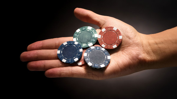 Sie sehen eine Hand in der vier Chips liegen.