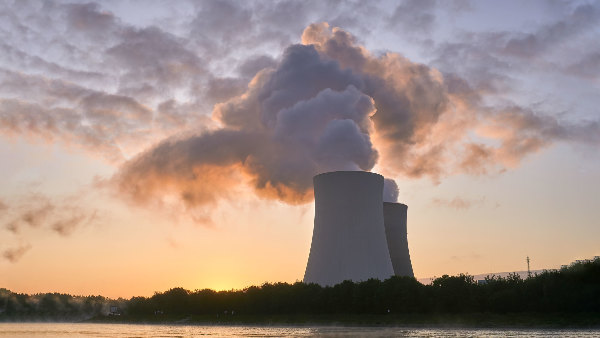 Sie sehen die Kühltürme eines Kernkraftwerks an einem Fluss.