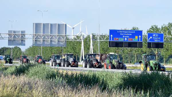 Sie sehen eine Reihe von Traktoren, die eine Autobahn blockieren.