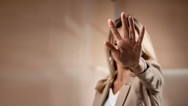 Sie sehen eine Frau mit abwehrender Hand.