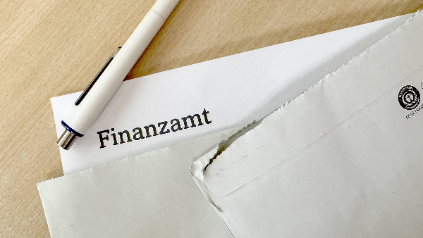 Sie sehen einen Brief von einem Finanzamt auf einem Tisch.