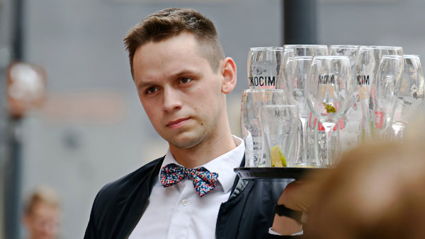 Sie sehen einen Kellner, der ein Tablett mit Gläsern trägt.