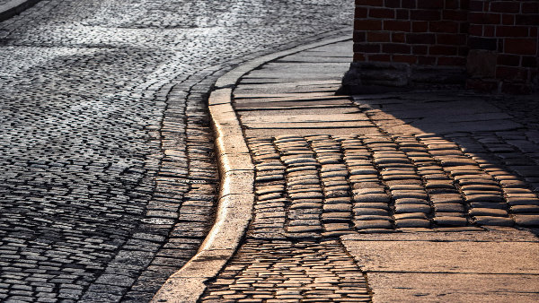 Sie sehen einen Ausschnitt eines Weges mit Kopfsteinpflaster.