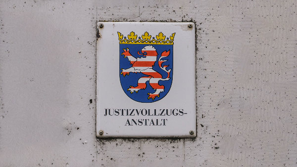 Sie sehen ein Schild mit dem Aufdruck &bdquo;Justizvollzugsanstalt&ldquo; und dem Wappen von Hessen.