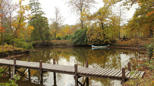 Sie sehen einen Teich mit einem Steg, auf dem ein Kanu schwimmt.
