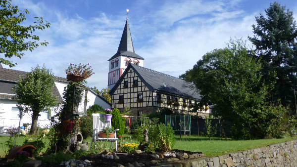 Sie sehen die Pfarrkirche St. Pankratius und davor einen dekorativen Garten.
