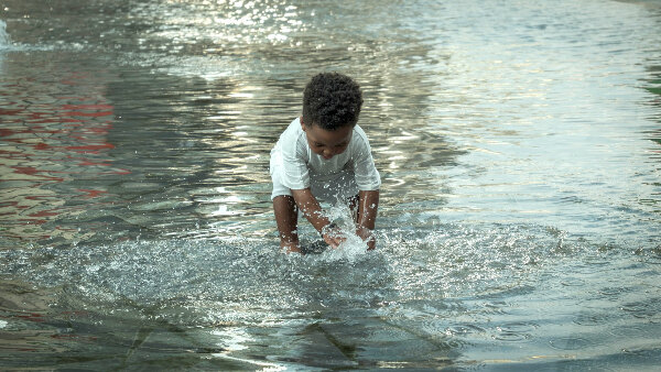 Sie sehen ein Kleinkind beim Planschen im Wasser.