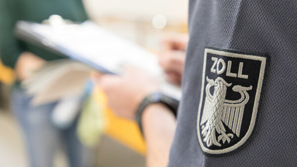 Sie sehen das Zollemblem auf dem Ärmel einer Jacke, als Teil der Dienstkleidung.