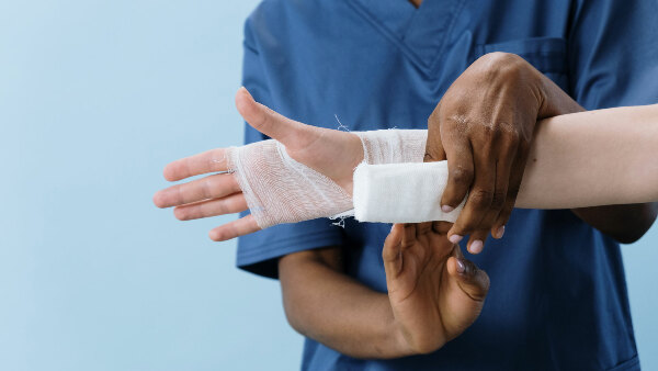 Sie sehen einen Krankenpfleger beim Anlegen eines Verbands.