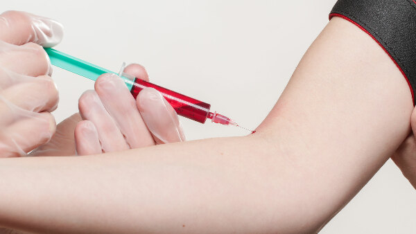 Sie sehen einen Arm von dem Blut abgenommen wird.