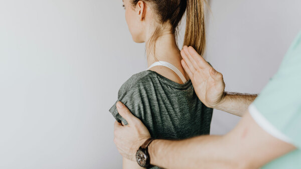Sie sehen einen Chiropraktiker, der die Wirbelsäule einer Patientin ein und konzentriert sich auf Ausrichtung und Korrektur der Körperhaltung in einer klinischen Umgebung.