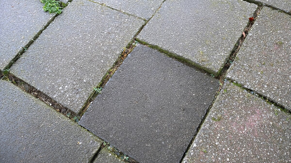 Sie sehen einen Gehweg miz einigen leicht schiefen Gehwegplatten.