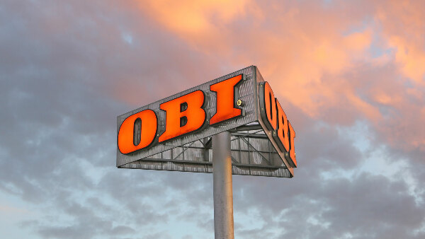 Sie sehen einen Mast mit Werbung der Baumarktkette &bdquo;OBI&ldquo;.