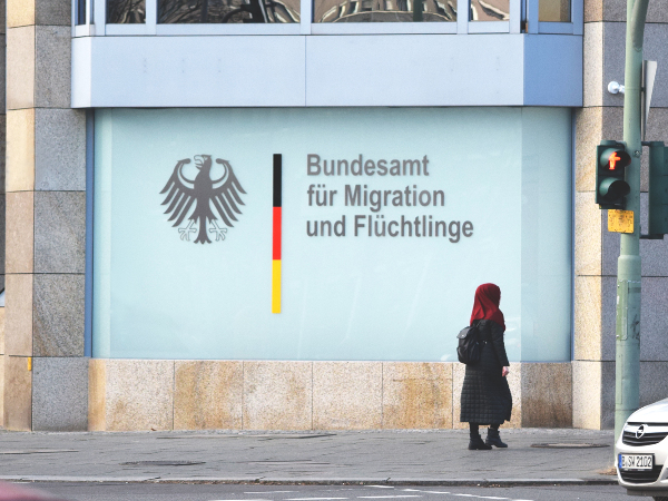 Sie sehen die Außenfassade einer Niederlassung des Bundesamt für Migration und Flüchtlinge (BAMF) mit dem Bundesadler und passendem Schriftzug der Behörde.