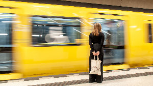 Sie sehen eine Frau vor einer einfahrenden U-Bahn.