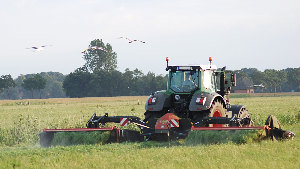 Sie sehen einen Traktor beim Mähen einer Wiese.