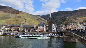 Sie sehen eine Sicht auf die Stadt Bernkastel-Kues mit einem Fahrgastschiff im Vordergrund.