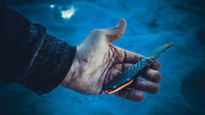 Sie sehen ein Messer in der Hand eines Mannes.