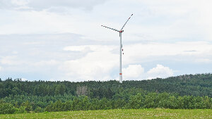 Sie sehen ein Windkraftwerk in einer Feldlandschaft.