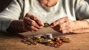 Sie sehen eine alte Person die ihr Kleingeld zählt.
