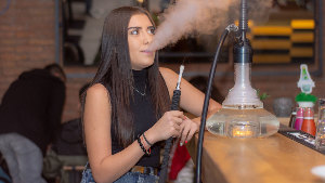 Sie sehen eine rauchende Frau in einer Shishabar.