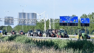 Sie sehen eine Reihe von Traktoren, die eine Autobahn blockieren.