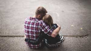 Sie sehen zweoi Jugendliche, die sich umarmen.