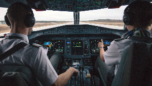 Sie sehen zwei Piloten in einem Cockpit eines Verkehrsflugzeugs.