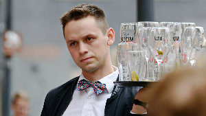 Sie sehen einen Kellner, der ein Tablett mit Gläsern trägt.