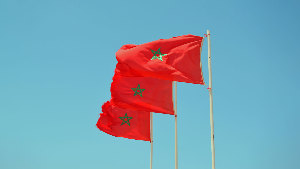 Sie sehen drei Fahnenmasten jeweils mit der Flagge des Konigreichs Marokko.