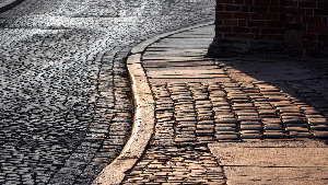 Sie sehen einen Ausschnitt eines Weges mit Kopfsteinpflaster.
