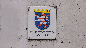Sie sehen ein Schild mit dem Aufdruck &bdquo;Justizvollzugsanstalt&ldquo; und dem Wappen von Hessen.