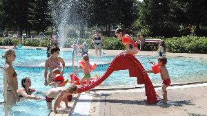 Sie sehen Kinder auf einer Wasserrutsche in einem Freibad.