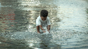 Sie sehen ein Kleinkind beim Planschen im Wasser.