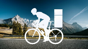 Sie sehen einen gezeichneten Radfahrer mit einem Kühlschrank auf dem Gepäckträger vor einer Berglandschaft