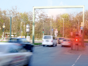 Sie sehen eine Straße mit Autos die durch eine Radarkontrolle geblitzt werden.